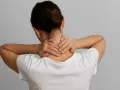 Kobieta masuje kark, szukając ulgi w bólu. Fizjoterapia plecy to rozwiązanie dla cierpiących.