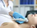 Fizjoterapeuta wykonuje badanie USG szyi, co może być częścią terapii stawu skroniowo-żuchwowego.