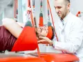 Fizjoterapeuta pomaga pacjentowi podczas terapii wiszącej. Często rehabilitacja kręgosłupa jest kluczowa dla powrotu do zdrowia.