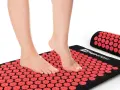 Stopy na macie do akupresury z czerwonymi rozetkami. Relaks i regeneracja dla stóp.