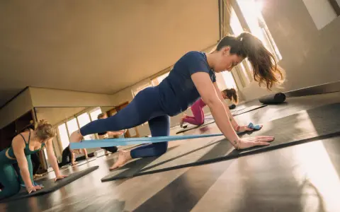 Kobiety wykonują ćwiczenia na ścięgno achillesa z taśmą oporową na macie.