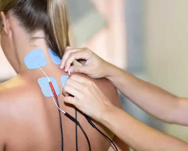 Elektrody na karku i plecach pacjentki, przygotowywane do zabiegu prądami na kręgosłup.